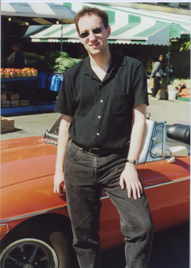 A younger version of me, posing in front of a car that isn't ours.